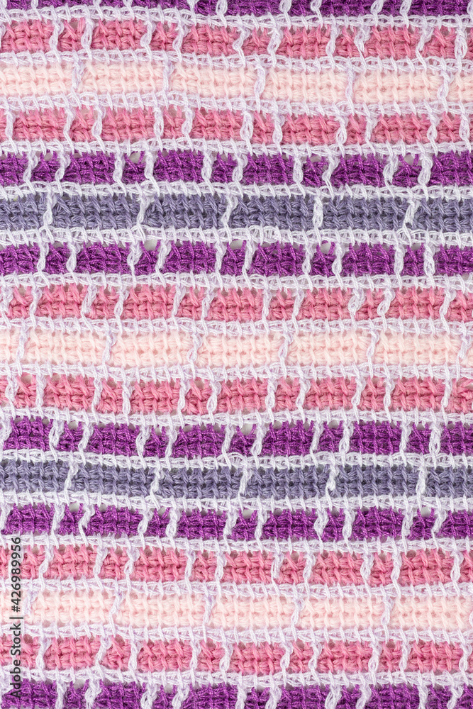 striped background of tunisian crochet fabric in basic stitch in shades of pink and purple with grid pattern