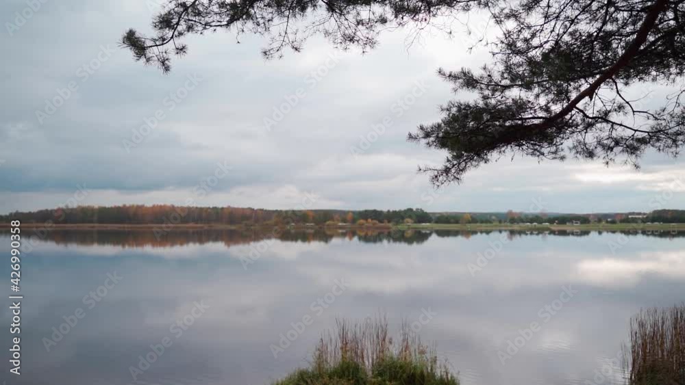 A beautiful colorful lake. The cloudy sky is reflected in the water. Autumn, the colorful foliage of the forest is visible A beautiful colorful lake. The cloudy sky is reflected in the water. Autumn, the colorful foliage of the forest is visible