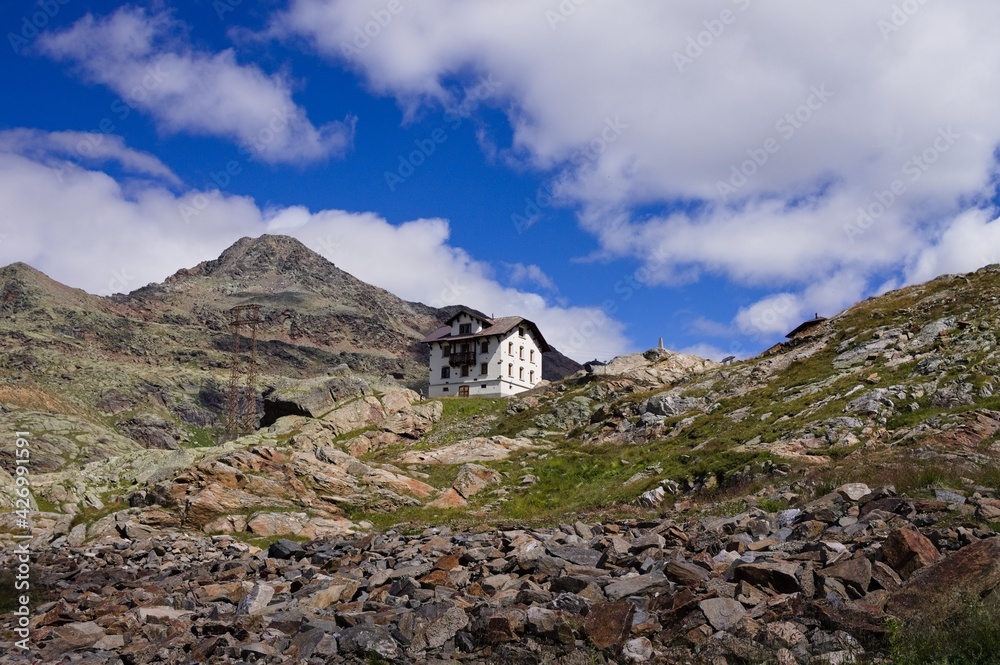 An isolated white house in the italian Alps with mountains and clouds in the background (Trentino, Italy, Europe) An isolated white house in the italian Alps with mountains and clouds in the background (Trentino, Italy, Europe)