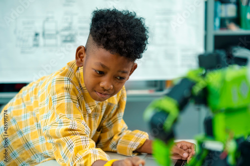 An african american boy is using laptop computer programming robot kit.