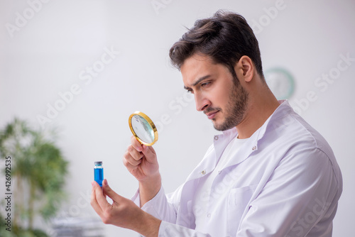 Young male chemist doctor holding vial