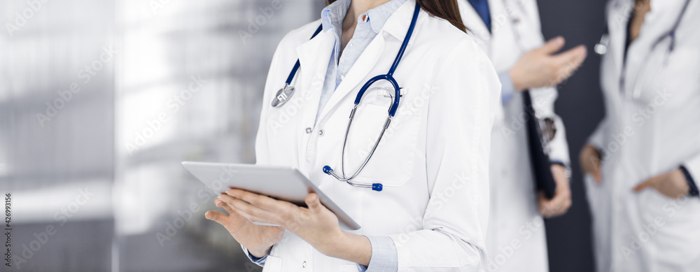 Unknown woman doctor iusing tablet computer in her hands, while standing in clinic. Medicine concept during Coronavirus pandemic Unknown woman doctor iusing tablet computer in her hands, while standing in clinic. Medicine concept during Coronavirus pandemic