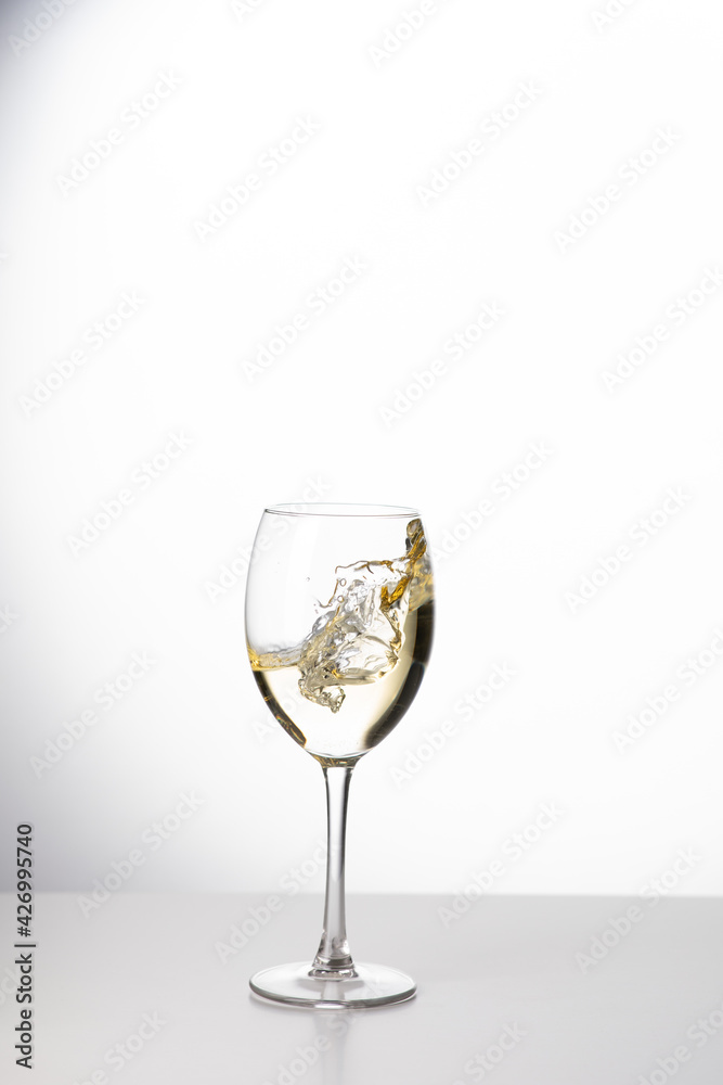 Weißwein im Weinglas mit weinspritzer aus dem glas Weißwein im Weinglas mit weinspritzer aus dem glas