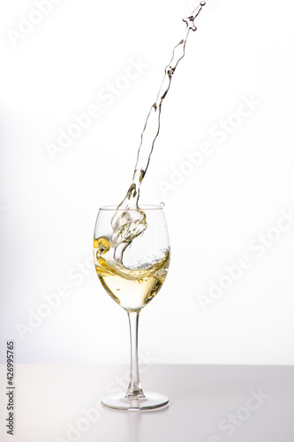 Weißwein im Weinglas mit weinspritzer aus dem glas