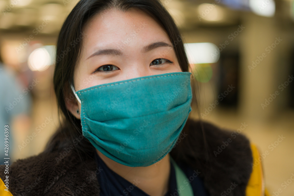 Asian woman flying in covid19 times - lifestyle portrait of young happy and pretty Chinese girl in face mask waiting on airport lounge ready for holiday trip