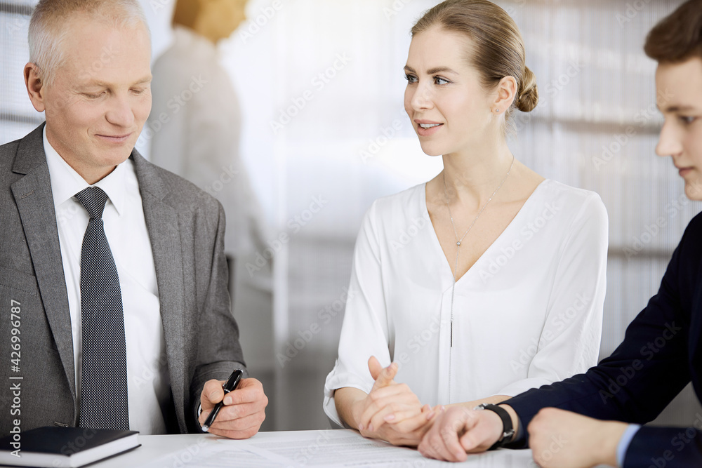 Elderly businessman and group of business people discussing contract in sunny office. Teamwork and cooperation Elderly businessman and group of business people discussing contract in sunny office. Teamwork and cooperation