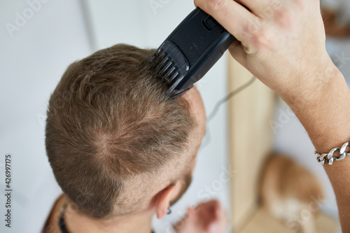 Принти на полотні Handsome man in white t-shirts cutting hair personally himself with machine trim