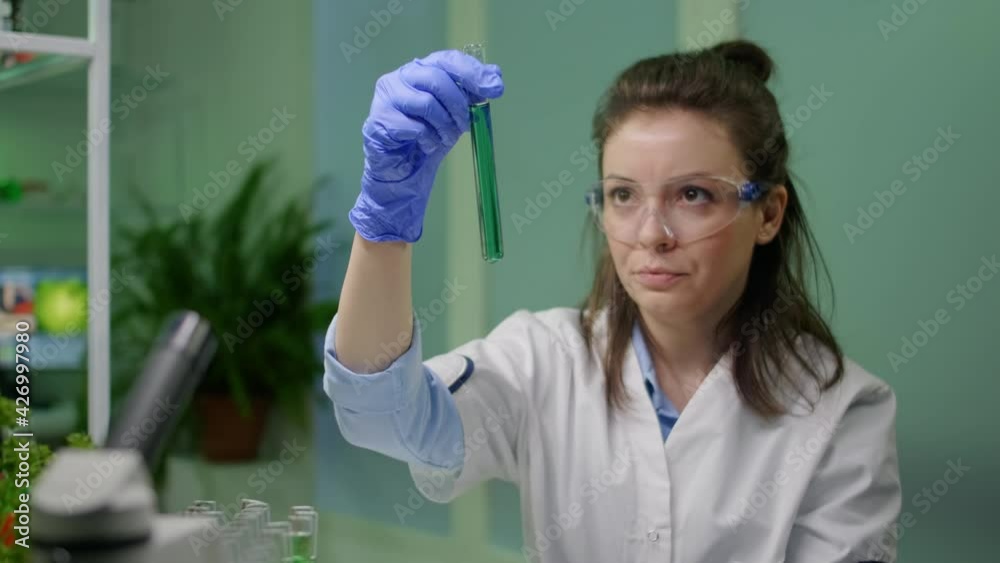 Chemist looking at test tube with geneticaly modified liquid for biology experiment. Biologist scientist researching chemical dna while working biochemistry agronomy laboratory Chemist looking at test tube with geneticaly modified liquid for biology experiment. Biologist scientist researching chemical dna while working biochemistry agronomy laboratory