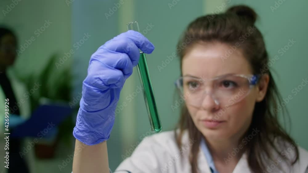 Closeup of scientist woman looking at test tube with dna sample examining for microbiology experiment. Researcher biologist working in agriculture laboratory developing gmo expertise on plants Closeup of scientist woman looking at test tube with dna sample examining for microbiology experiment. Researcher biologist working in agriculture laboratory developing gmo expertise on plants