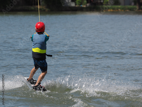 Back side of asian boy learning to wake-board