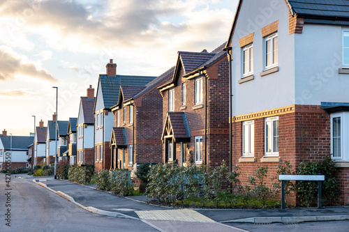 Fototapeta Naklejka Na Ścianę i Meble -  Houses in England with typical red bricks at sunset - Main street in a new estate with typical British houses on the side - Real estate and buildings concepts in UK