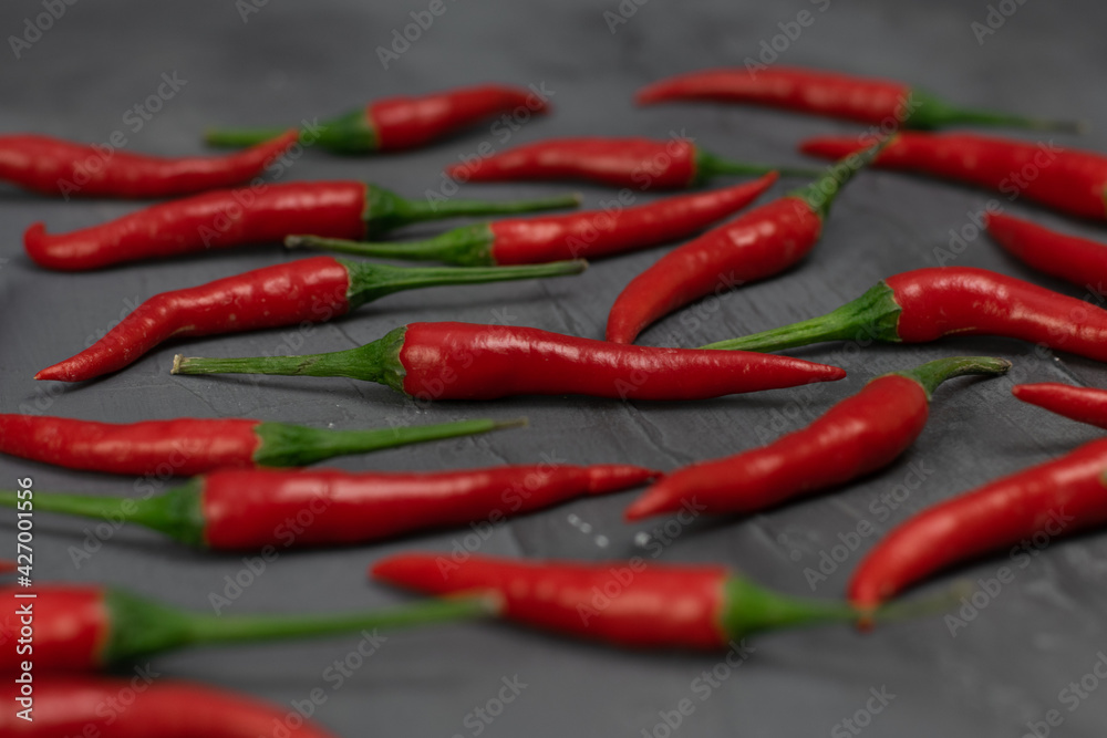 Red chilli peppers on dark gray stone background.
