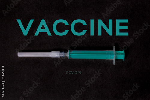coronavirus vaccine covid 19. turquoise syringe on a black background