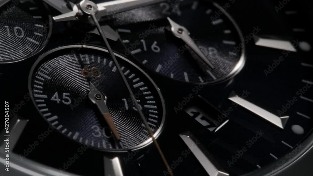 Silver red second arrow running on the dark blue clockface of luxury swiss watch with chronograph. Light flash on the turning clockface with metallic details. Closeup macro view Silver red second arrow running on the dark blue clockface of luxury swiss watch with chronograph. Light flash on the turning clockface with metallic details. Closeup macro view