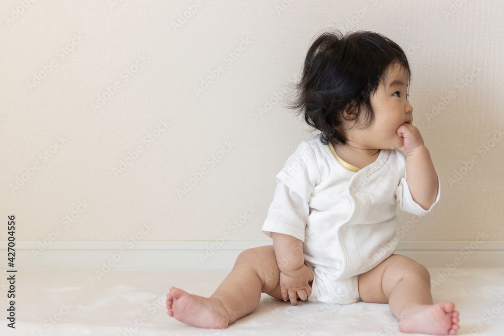 絨毯の上に座る赤ちゃん（0歳、生後9か月、日本人、女の子）