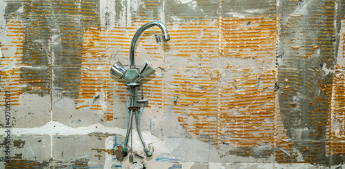 Old grungy concrete wall with shower faucet  as background or texture. Bathroom reparations photo