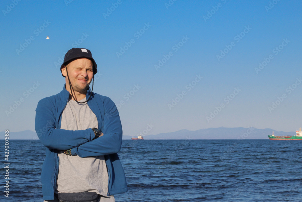 A man in a hat against the backdrop of a seascape.