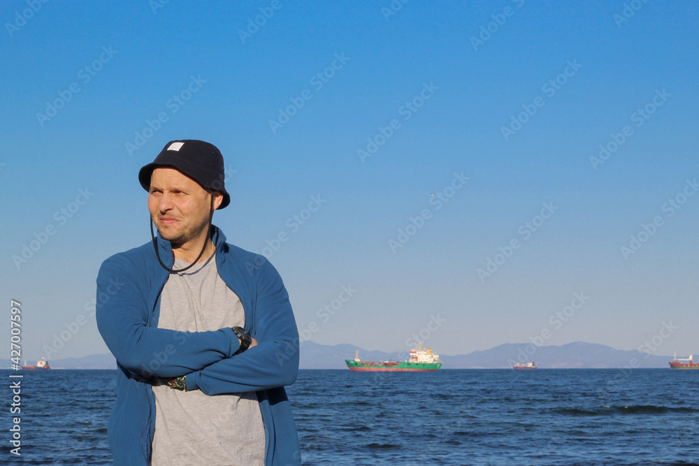 A man in a hat against the backdrop of a seascape.
