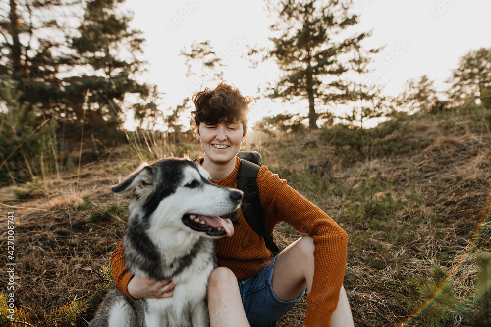 Junger Backpacker sitz gemeinsam mit Hund in der Natur Junger Backpacker sitz gemeinsam mit Hund in der Natur