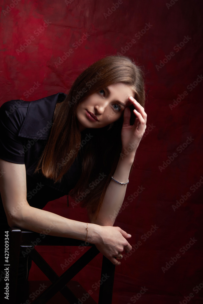 Portrait of a young woman with long brown hair, on a red textured background