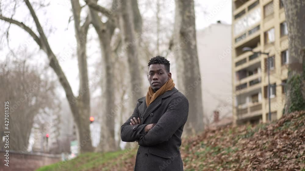 Young black man standing outside wearing coat and scarf looking at camera portrait Young black man standing outside wearing coat and scarf looking at camera portrait