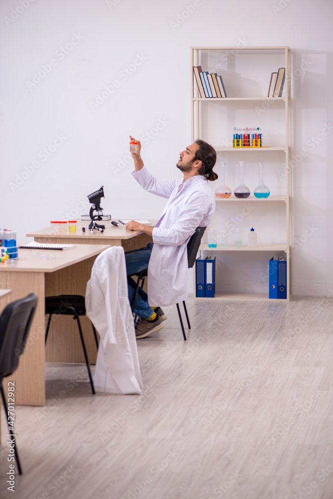 Young male chemist sitting at the desk in the classroom Young male chemist sitting at the desk in the classroom