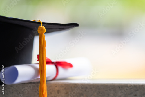 Close-up of a mortarboard and degree certificate put on table. Education stock photo