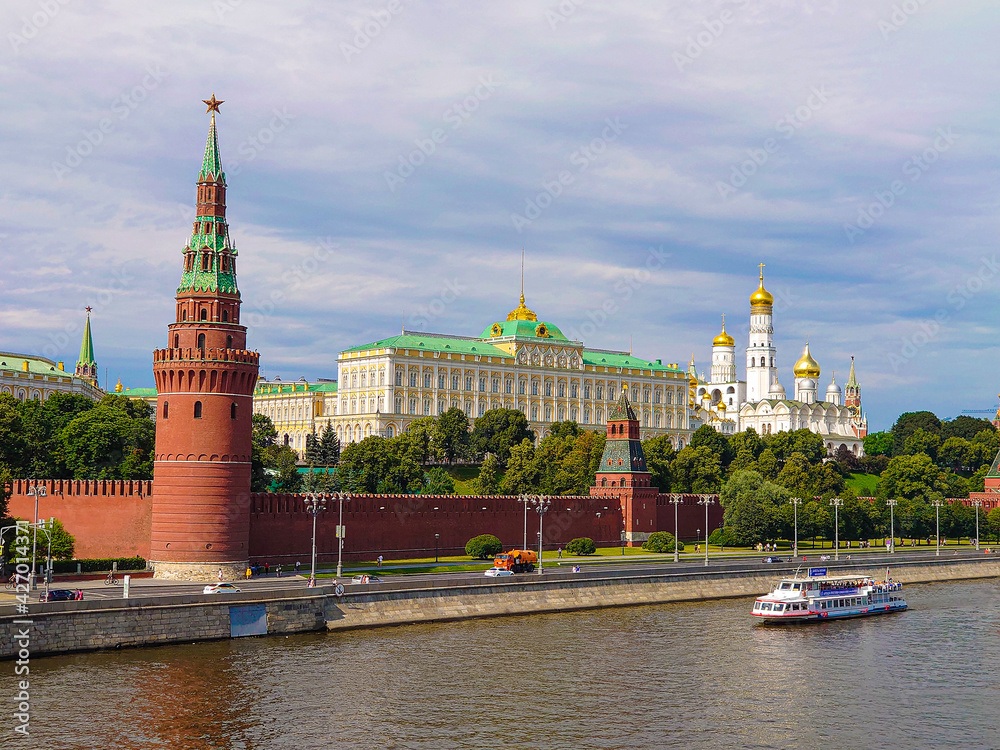 main view of the Moscow Kremlin, street cleaning is underway, a pleasure boat is sailing along the river