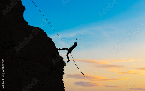Rock climber silhouette on sunset.