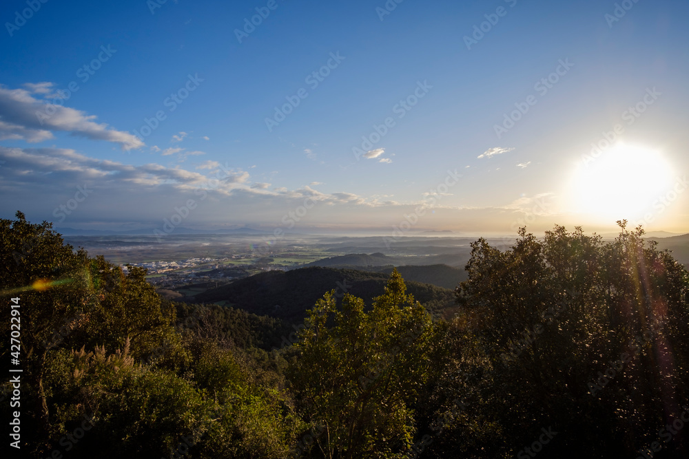 Sun rising on a green mountain landscape from the top of a hill in Costa Brava