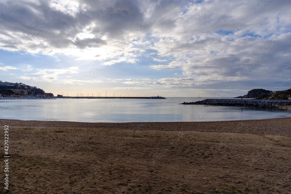 Empty sandy beach landscape on a quiet water scene under a cloudscape sky