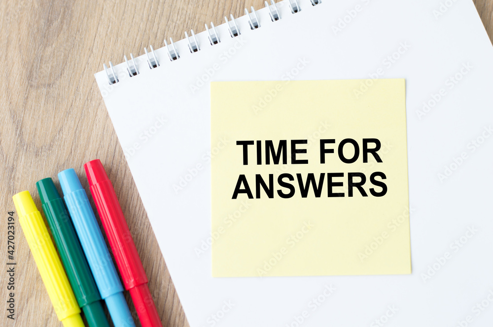 White notebook on which yellow paper is led with the text TIME FOR ANSWER on a wooden table White notebook on which yellow paper is led with the text TIME FOR ANSWER on a wooden table