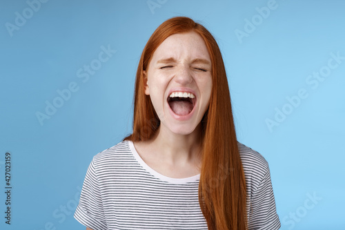 Girl screaming out loud showing attitude take out stress being fed up complaining hursh life shouting closed eyes yelling pissed standing bothered distressed blue background photo