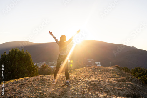 Woman standing, looking on sunrize in mountains