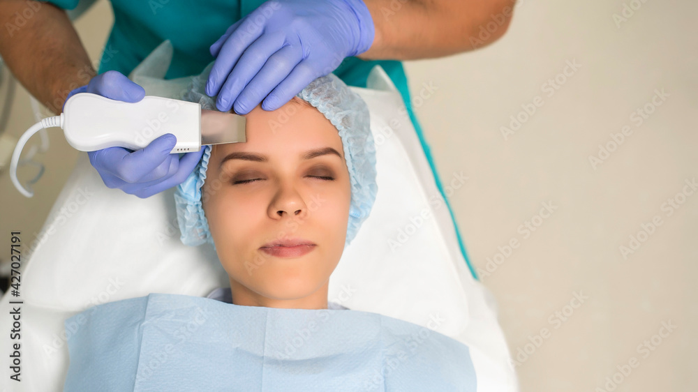 Close up cosmetologist hands in gloves making ultrasound cleaning procedure to the patient's face with perfect skin.