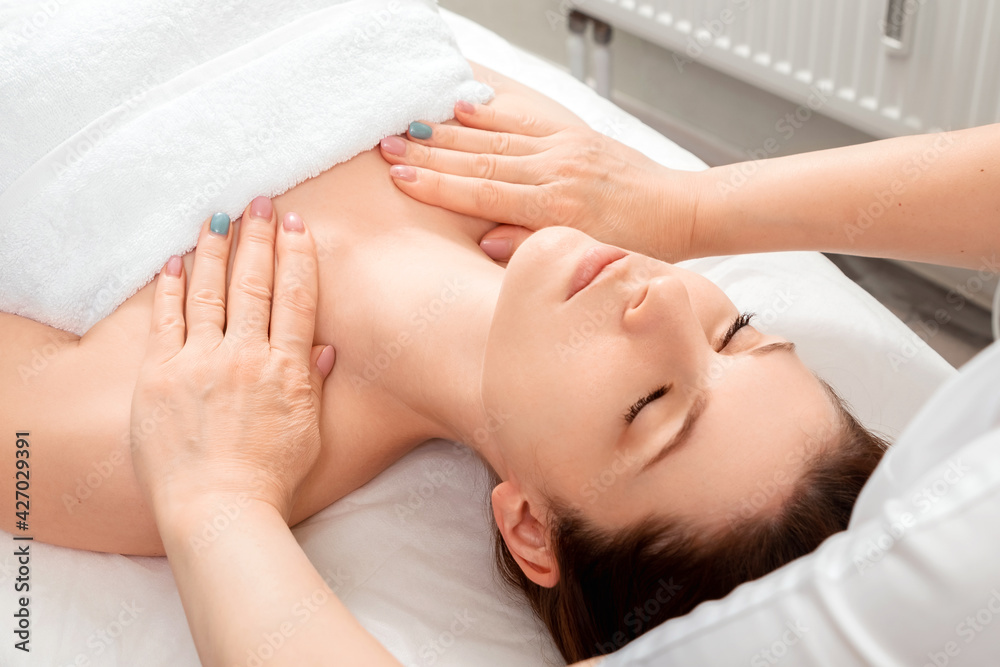 A massage is being done on the face of a beautiful girl, close-up. Skin care, beautician, spa treatments, facial hygiene.