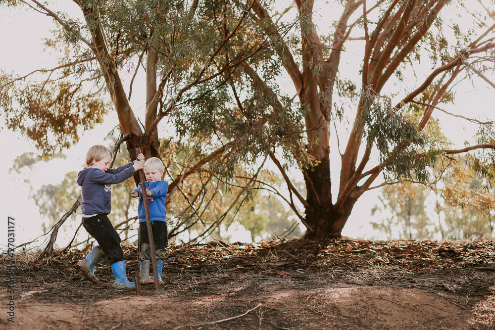 Cute little caucasian boys playing in nature wearing blue gumboots Cute little caucasian boys playing in nature wearing blue gumboots