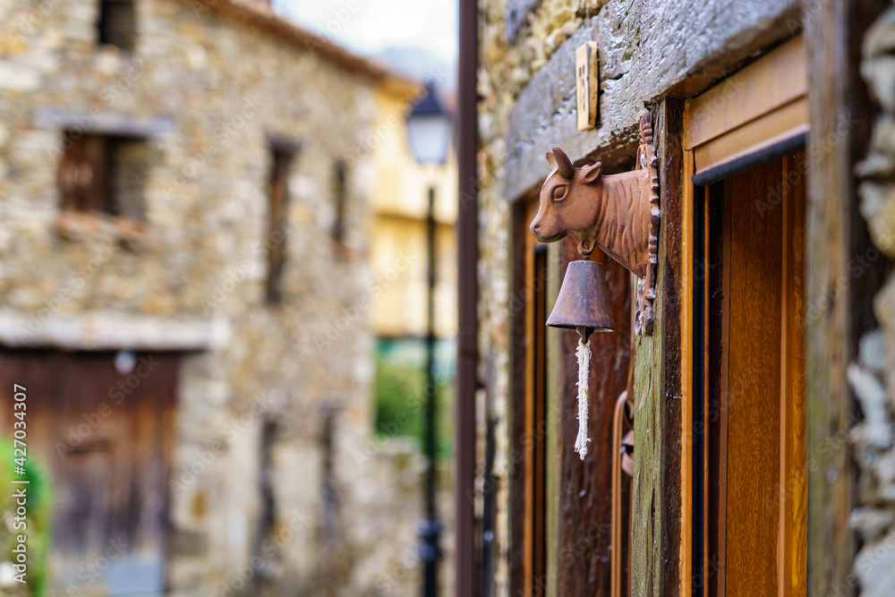 Detail of door bell with cow's head in old stone village. La Hiruela Madrid.