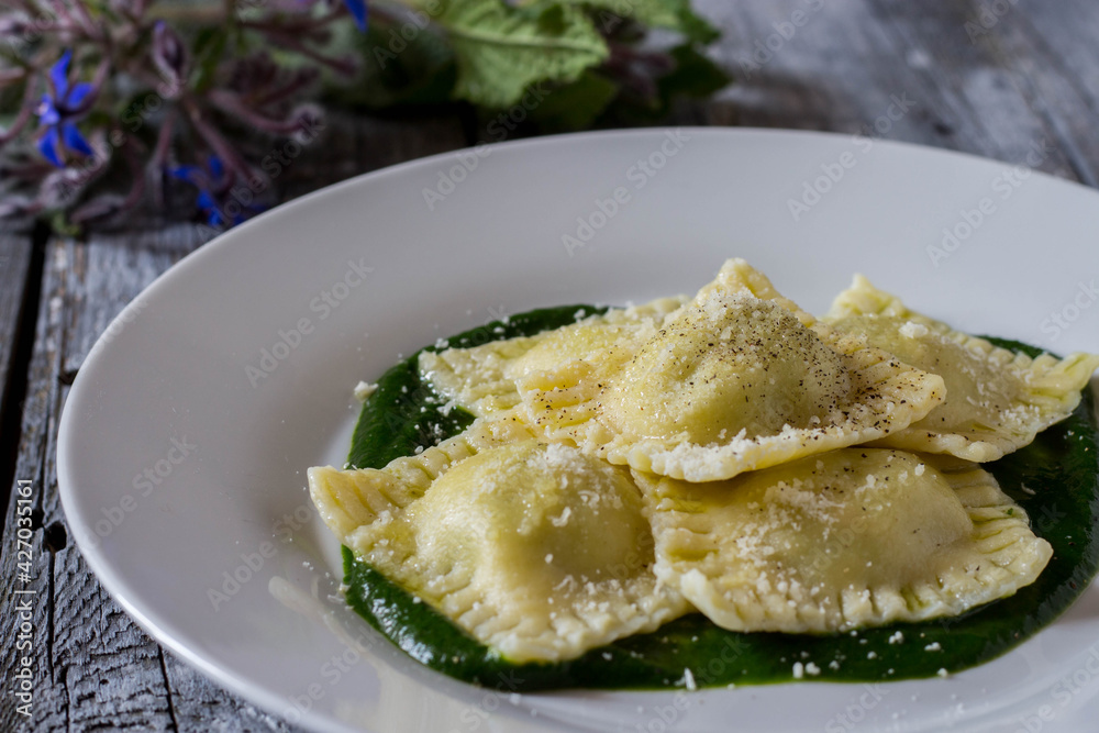 Ravioli stuffed with potatoes and carrots on a bed of borage puree with a sprinkling of Parmesan cheese and black pepper