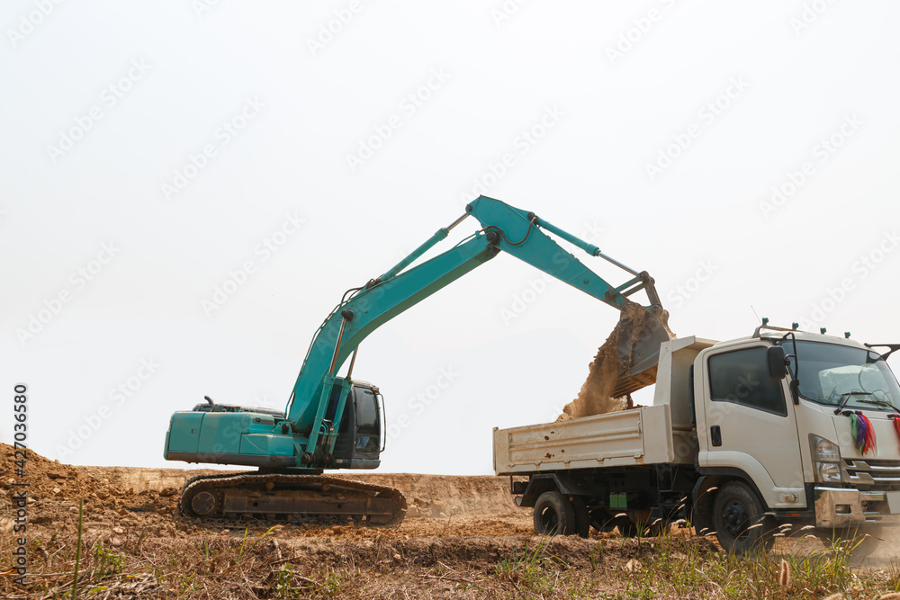 Crawler Excavator digging the soil into a truck ,In the construction site on white background . Crawler Excavator digging the soil into a truck ,In the construction site on white background .