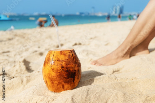 Fototapeta Naklejka Na Ścianę i Meble -  Sweet coconut drink on the sandy beach. The concept of rest and vacation in a tropical resort