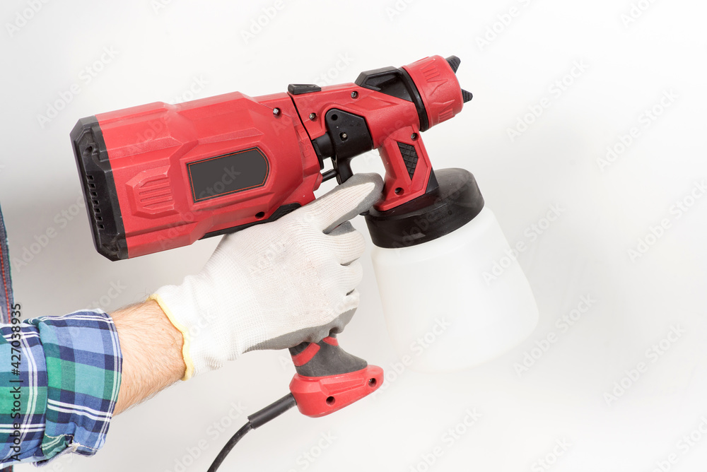A builder paints a wall with an electric spray gun, a close-up, during a house renovation, renovation.