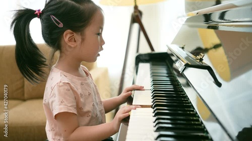 Medium close up shot of Asian girl toddler practice piano with happy and fun, Music class learning at home.
