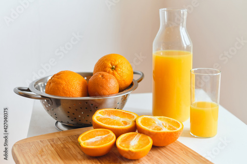 Glass of fresh natural orange juice on the table for a cheerful morning. Sliced juicy oranges for making fresh juice on a wooden board. Vitamin drink for breakfast. Healthy lifestyle  natural products