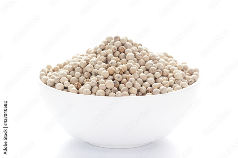 close-up of Organic White peppercorns (Piper nigrum) on a ceramic white bowl. Pile of Indian Aromatic Spice. close-up of Organic White peppercorns (Piper nigrum) on a ceramic white bowl. Pile of Indian Aromatic Spice.
