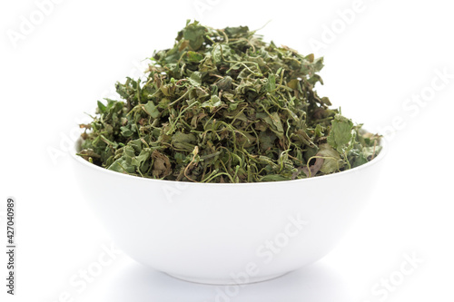 close-up of Organic green dry Fenugreek leaves (Trigonella foenum-graecum) on a ceramic white bowl. Pile of Indian Aromatic Spice photo