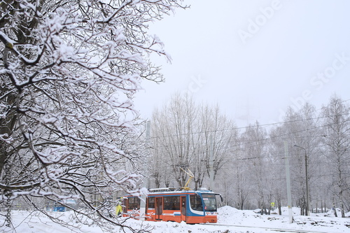 a colored tram passing on the background of a winter landscape