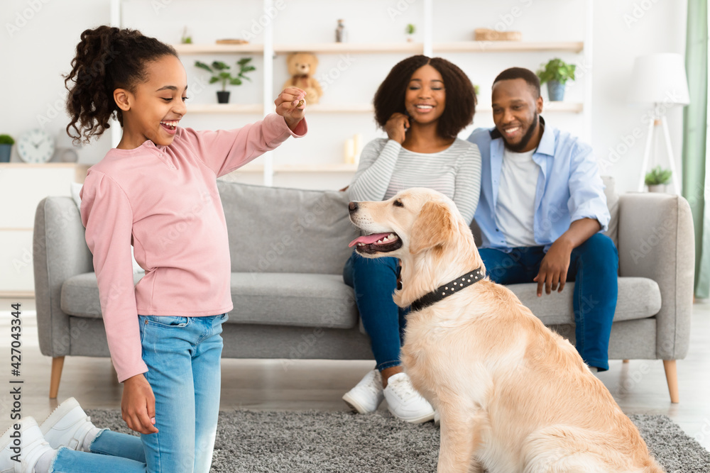 Black girl giving a treat to her obedient dog