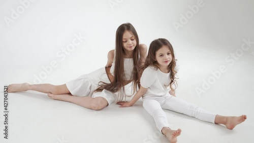 little girls with long hair in white clothes play, indulge and tickle each other