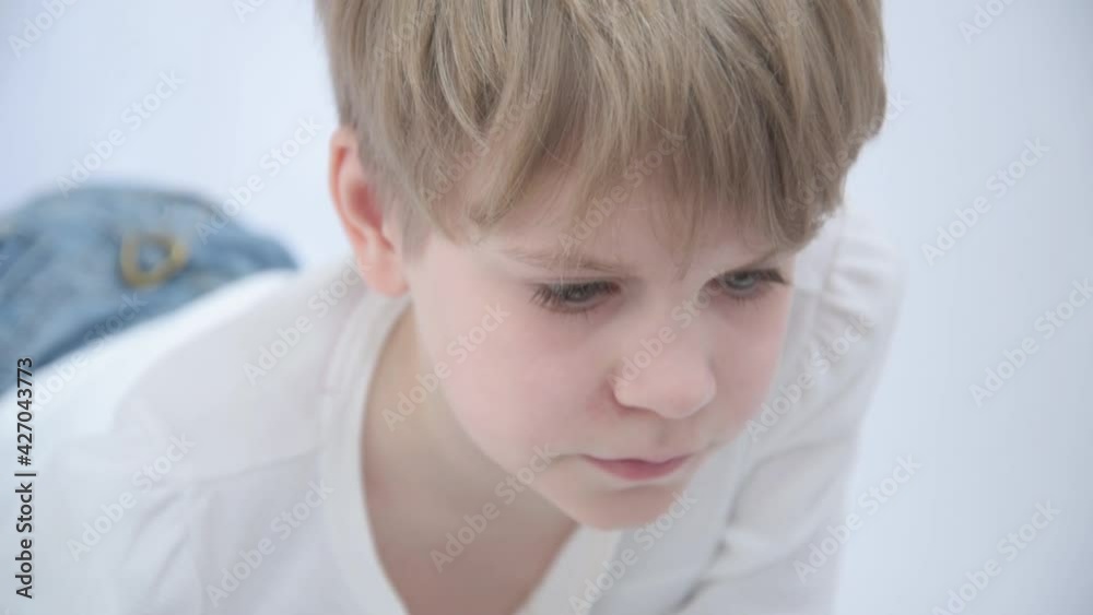 The blond child looks attentively at the computer or laptop screen. Close-up portrait The blond child looks attentively at the computer or laptop screen. Close-up portrait